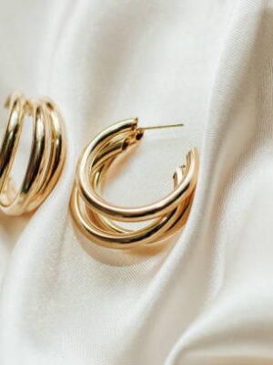 Gold jewelry earrings made of gold on the background of silk.