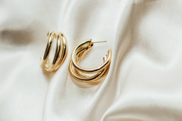 Gold jewelry earrings made of gold on the background of silk.